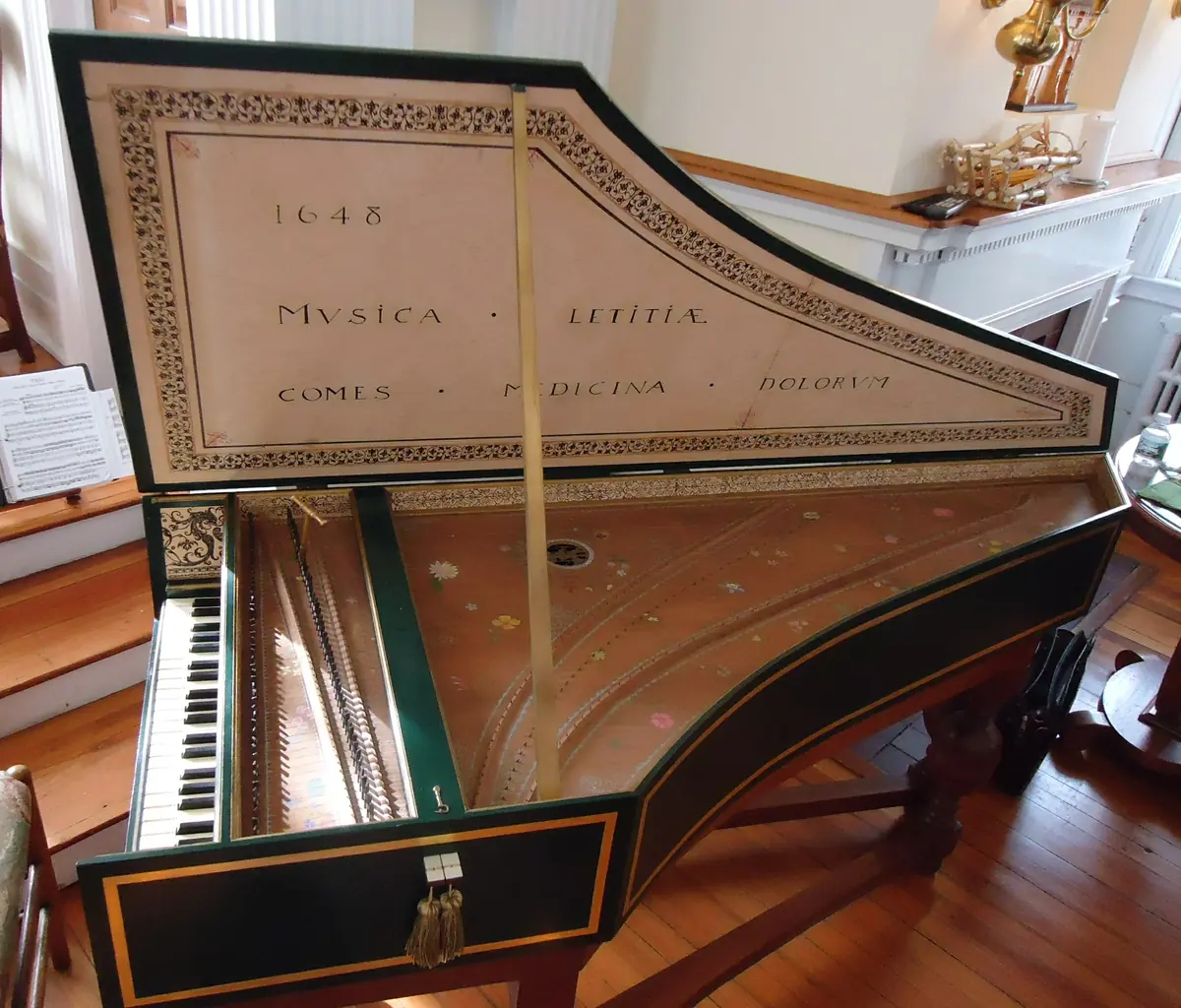 A harpsichord with its lid open, a painted soundboard and a keyboard, in a church interior